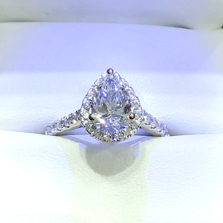 18kt White Gold Engagement Ring with 1.5 carat lab diamond at the center (Color: E | Clarity: VS1 | Pear Cut) and natural E / VVS grade Setting Diamonds. Cathedral Halo Setting with Diamonds on the prongs.